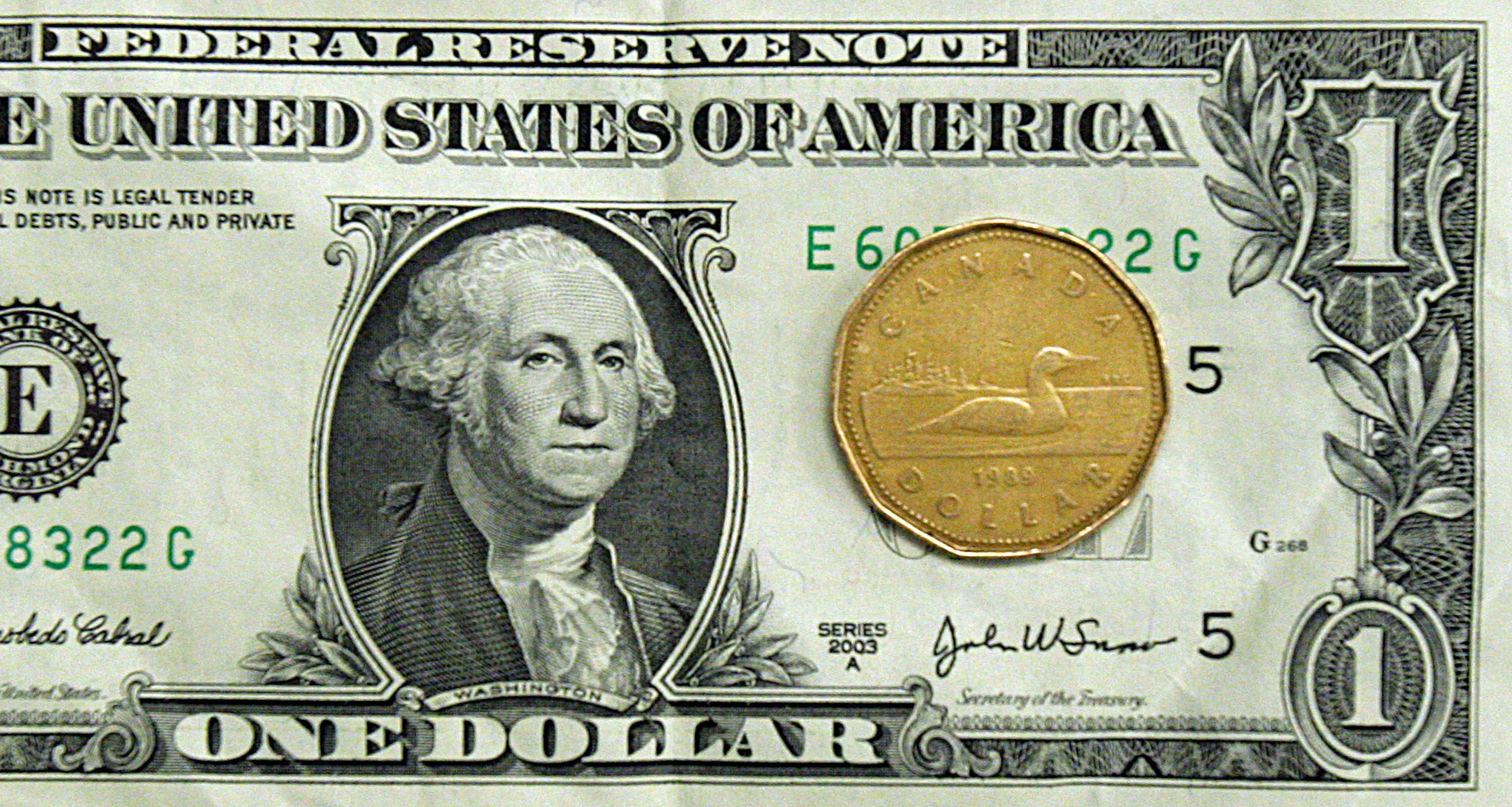 在經濟衰退期間，加元貶值77美分，現已回到與美元等值的水平。圖為美金一元紙鈔和加幣一元銅板。