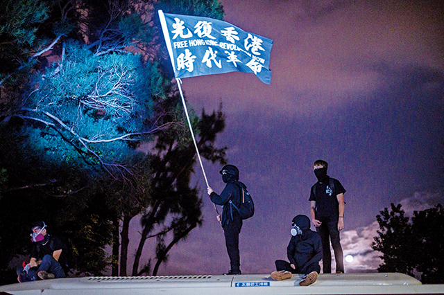 2019年11月12日警察與香港中大校園內的抗議者發生衝突期間，警方向學生和抗議者發出催淚彈後，一名抗議者揮舞著一面旗幟，上面寫著「光復香港，時代革命」。Getty Images