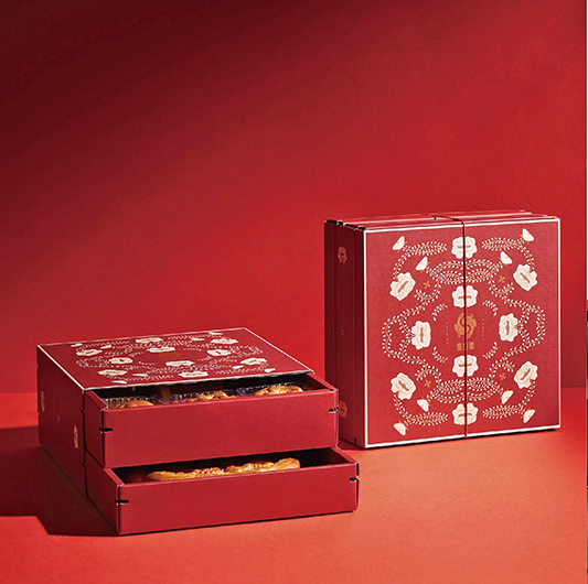 喜豐香餅舖的喜餅餅盒上，不是常見的豔紅，而是淡雅的玫瑰紅，花草紋匍匐在盒面上，團團圍著一對相互依偎的喜鵲。喜豐香提供