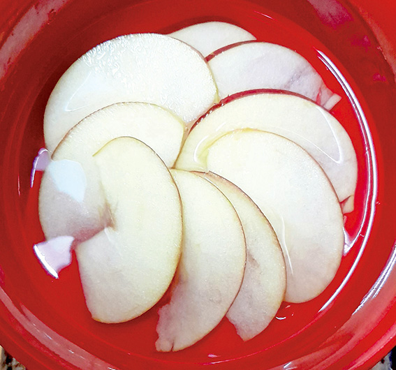 取1顆蘋果切半月型薄片，排成圓形狀平鋪至欲製作之果凍容器底部。
