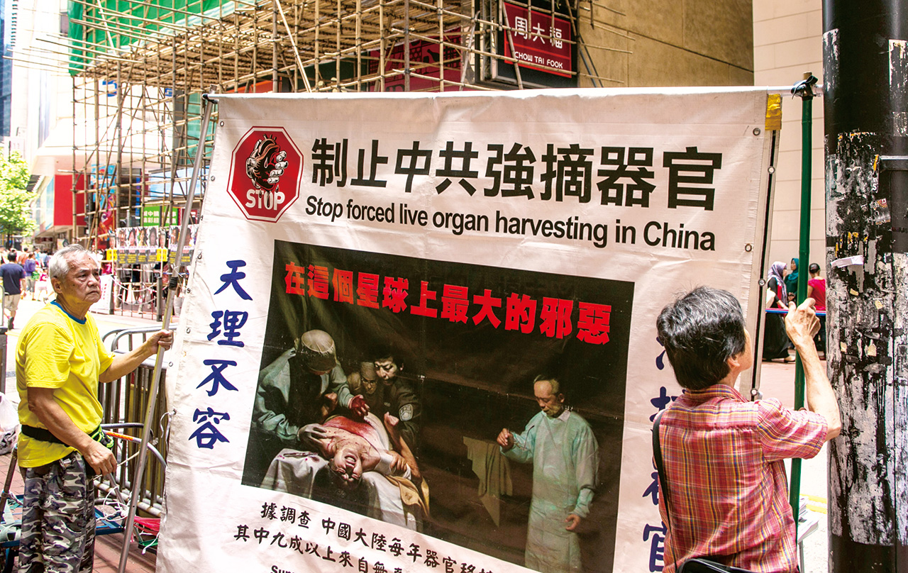 青少年離奇失蹤事件，引發民間對活摘器官不安。圖為2014年5月25日，示威者在香港時代廣場附近懸掛抗議非法器官移植的廣告看板。Getty Images