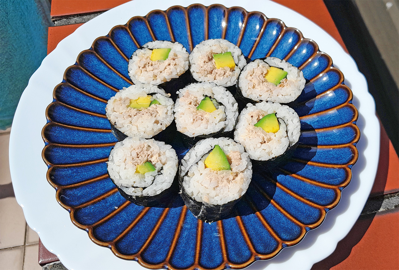在竹簾上放上一片海苔，海苔粗糙面朝上。在海苔上平鋪一層均勻的白飯，注意白飯不要鋪太厚，否則難捲容易散開。海苔最上邊預留約3公分的面積不鋪白飯。