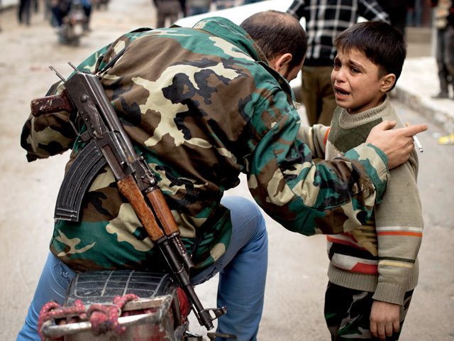 叙利亚反抗军士兵正在安抚一位7岁叙利亚孩童，他的母亲生死不明，父亲据称死于政府军枪下。Getty Images