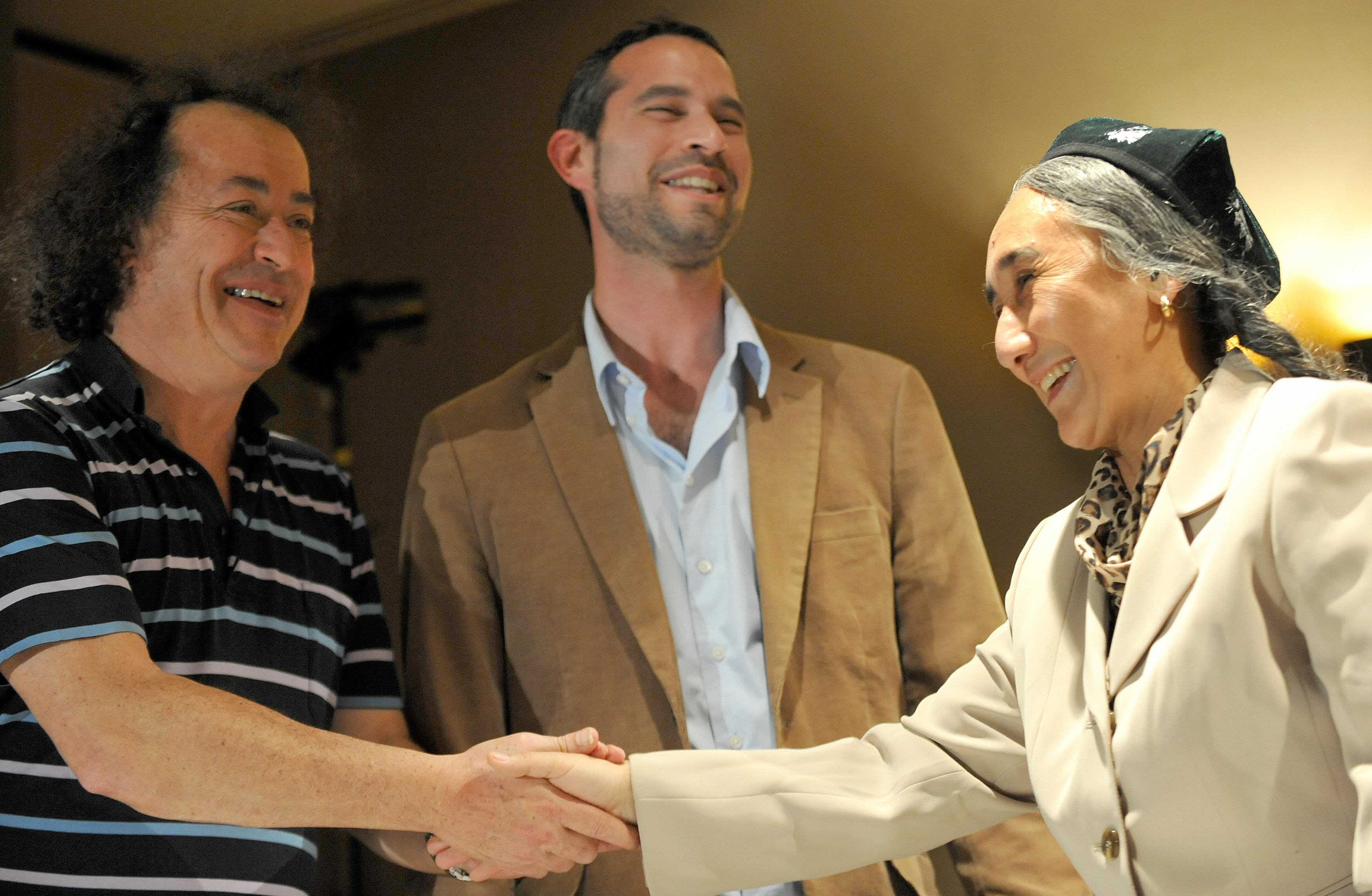 8月5日，墨尔本国际电影节主席李查‧穆尔（左）与纪录片《爱的十个条件》导演杰夫‧丹尼尔（中）、维吾尔族传奇人物热比娅‧卡德尔（右）在影片放映前的记者会上谈笑握手