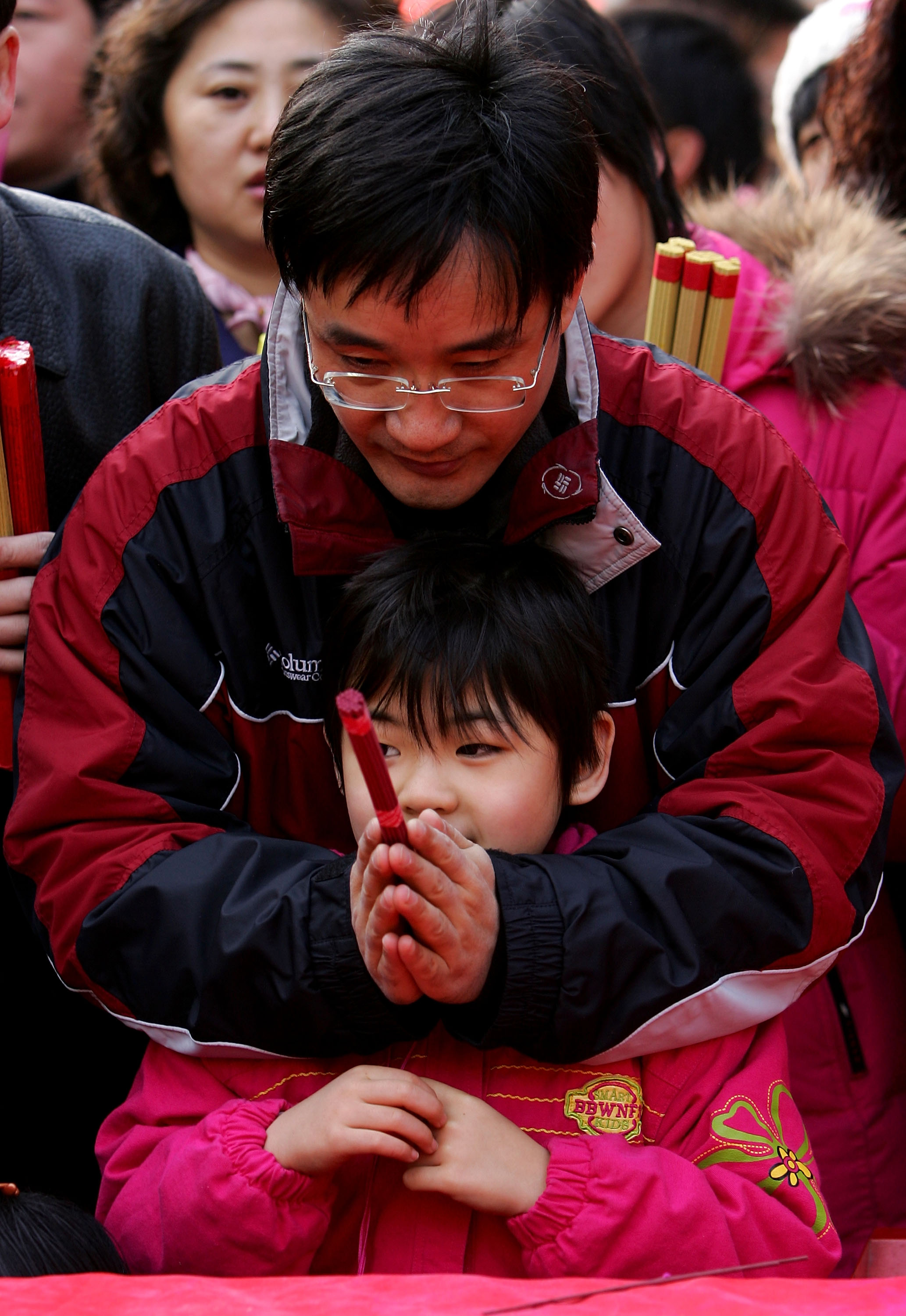 亲子关系中，父母的教育理念很重要。图为北京白云寺，一位父亲和女儿一起祈祷。