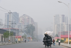 10月19日，一輛三輪車在北京正午因空氣污染而灰濛的街頭行走。似乎也象徵這一波中國經濟的疲軟不振。